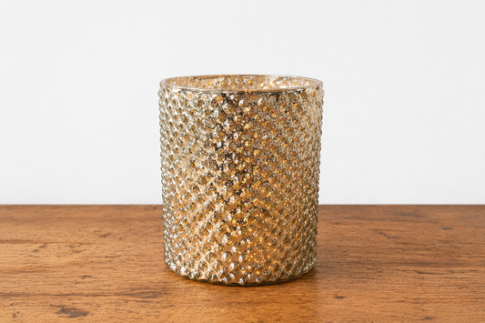 Decorative gold candle holder on a wooden surface with a white background